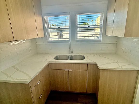 Renovated kitchen with stone counters and light wood cabinetry at the Hollywood Bungalows